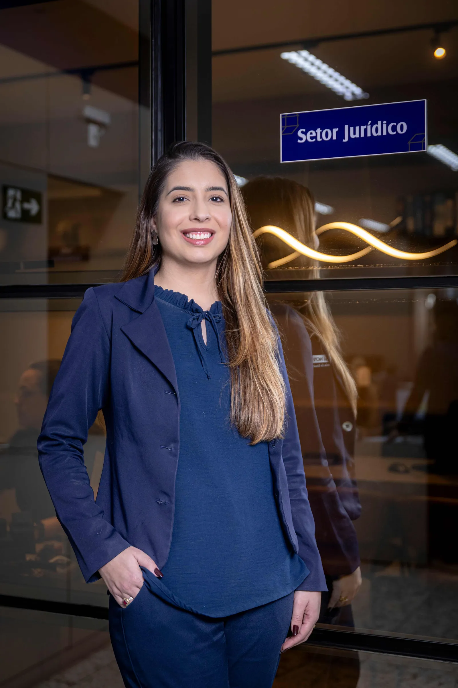 Profissional da Casa Nova em frente à placa do Setor Jurídico, na sede da imobiliária em Divinópolis